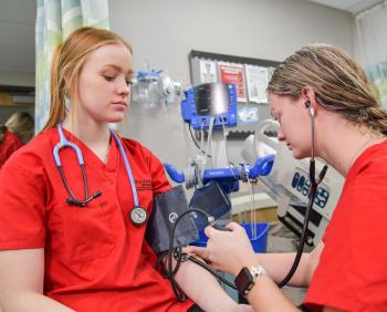在靠谱的网络彩票平台的BSN护理项目的学生测量彼此的血压.
